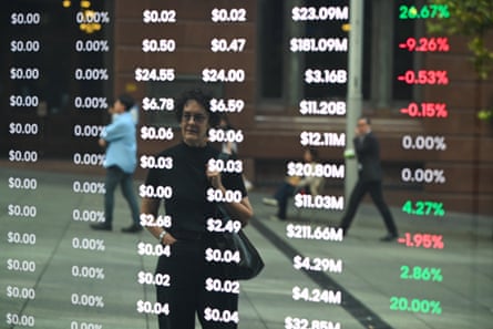 A woman is seen reflected in a screen showing stock information at the Australian Securities Exchange (ASX) headquarters in Sydney