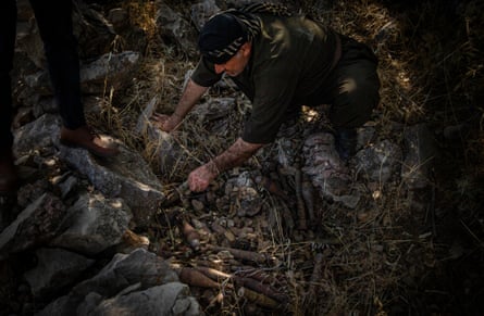 Rizgar Ali examines a mortar shell and RPG cache hidden behind a defensive wall in Serdera Village near Penjwen, Iraqi Kurdistan. The defensive wall and the explosives are Iraq-Iran War remnants.