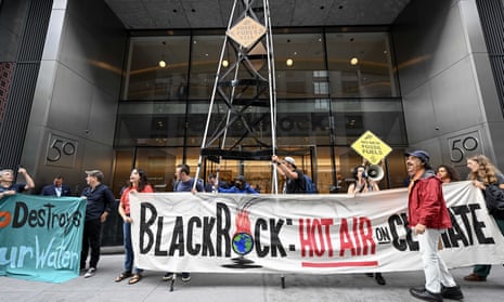 Climate activists hold banners in front of the headquarters of BlackRock in New York.