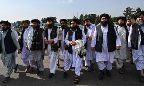 Taliban spokesperson Zabihullah Mujahid (centre, holding shawl) a accompanied by officials to address a media conference on 31 August.