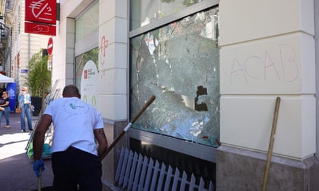 A cleaning contractor shifts debris next to a damaged window of a Caisse d’Epargne bank in the centre of Marseille