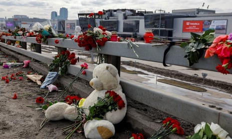 Flowers and toys are placed on the roadside in front of the burnt-out Crocus City Hall after a deadly attack on the concert venue on the outskirts of Moscow