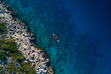 An aerial view of someone in a sea kayak near a rocky coast
