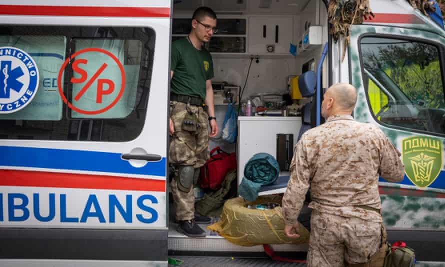 A Ukrainian/German medic (left) talks as he cleans an ambulance in Bahkmut