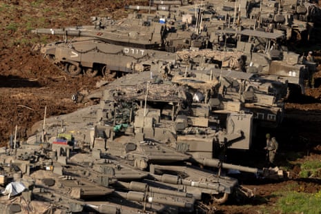 A soldier walks by Israeli tanks in position near the border with Lebanon in Northern Israel.