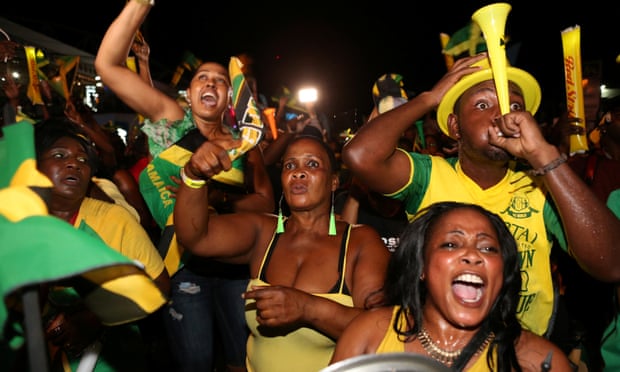 Fans cheer while watching a broadcast of Jamaica's Usain Bolt winning the men's 100 meters final and becoming the first man to win three successive Olympic titles on the track, in Kingston, Jamaica