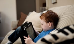 Small boy sitting on sofa looking at a tablet