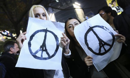 People in Tokyo show solidarity with victims of Paris terrorist attacks, with the Eiffel Tower peace symbol designed by Jean Jullien.