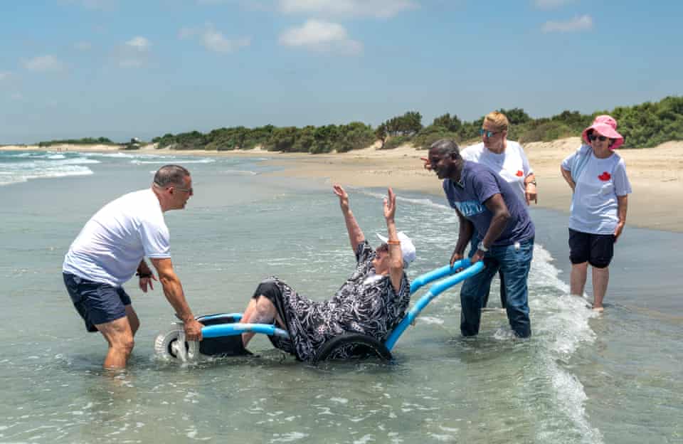Eliran Keren, the son of a Holocaust survivor along with Segal assist Judith, a holocaust survivor in her 80s, into the Mediterranean Sea at the beach at Kibbutz Magen Michael in Israel.