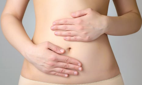 A woman holds her two hands on her belly