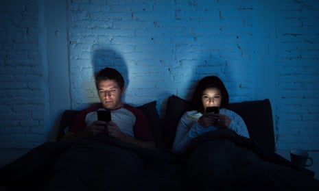 Молодая пара на своих телефонах в постели