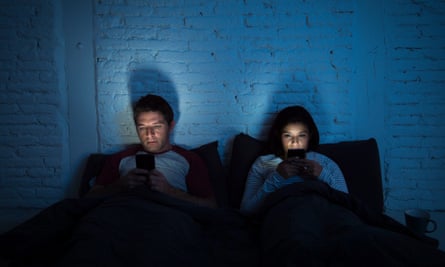 couple in bed reading their phones