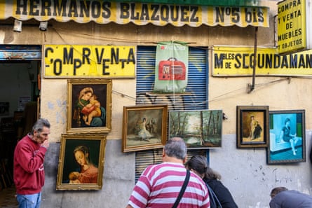 A secondhand art shop in Madrid with people studying the paintings.