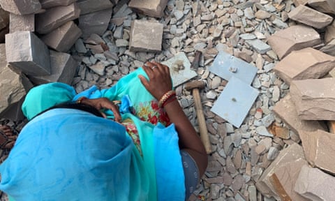 A woman sits amid the rubble with her tools-- a hammer and a chisel in Budhpura, Rajasthan, India