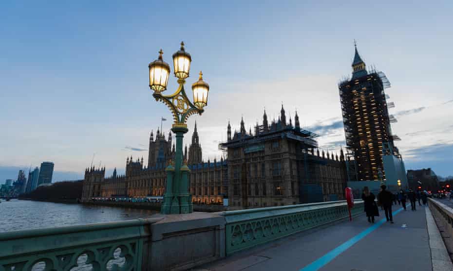 People walk along Westminster Bridge past the Houses of Parliament and Big Ben.