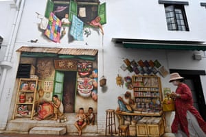 Singapore. A woman walks past a realistic mural painted on to the wall of a building