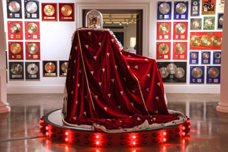 A red velvet cloak on a podium, in a room surrounded by gold discs on the wall