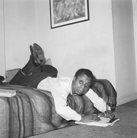 James Baldwin sprawls across the bed in his New York apartment to jot some notes down.