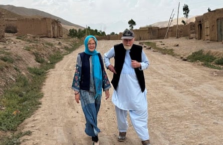 Peter and Barbie Reynolds walking along a rural dirt road with small buildings in the background