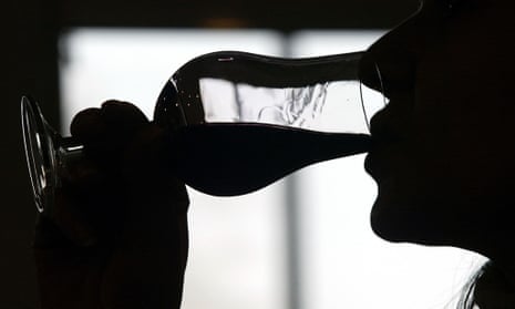 A silhouette of someone sipping from a glass of red wine
