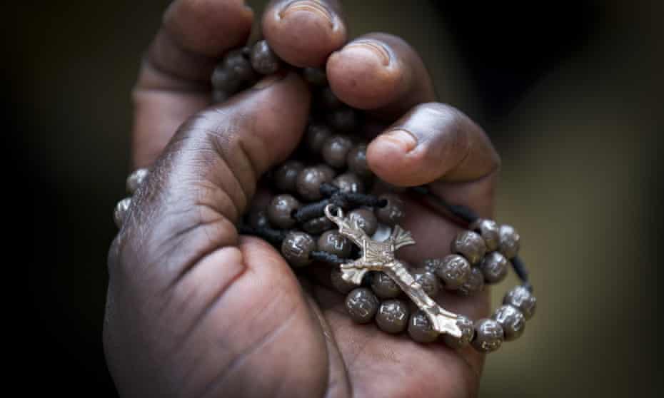 A woman clutches her crucifix and rosary beads as Pope Francis leads a mass in Uganda in November 2015