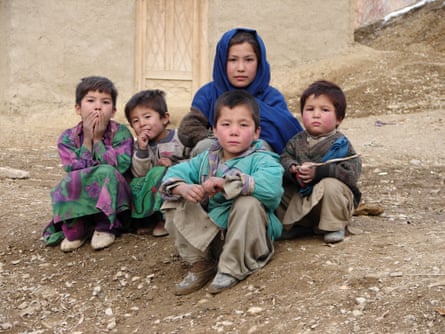 Five children sitting on dirt ground