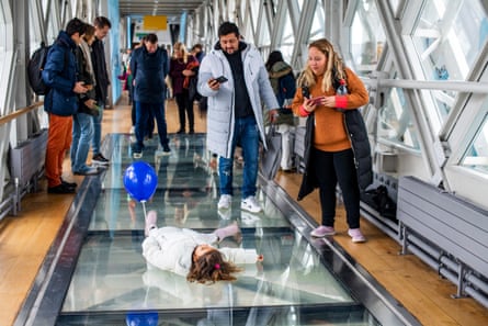 Visitors braving the glass floor in the high -level walkway on Tower Bridge. It provides a fantastic view to the road and river thames below, particularly when a bridge lift is scheduled.