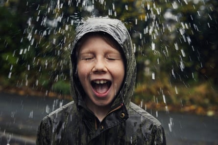 Happy smiling boy getting wet in rain outdoors