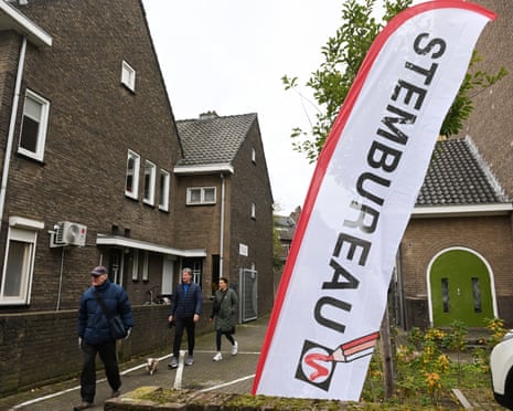 People walk past a banner leading them to the nearest polling station during general elections in Maastricht, Netherlands.