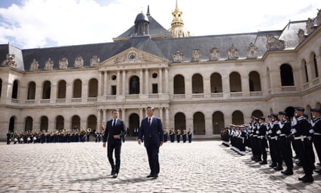 Emmanuel Macron and Xi Jinping walk in the middle of a large courtyard as they review an assembly of guards during an official welcome ceremony