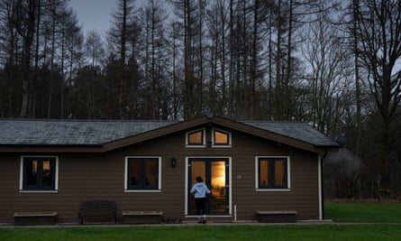 A brown cabin in front of some woodland.