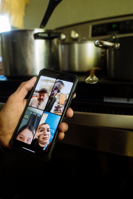 Hand holds smartphone with four people on video call