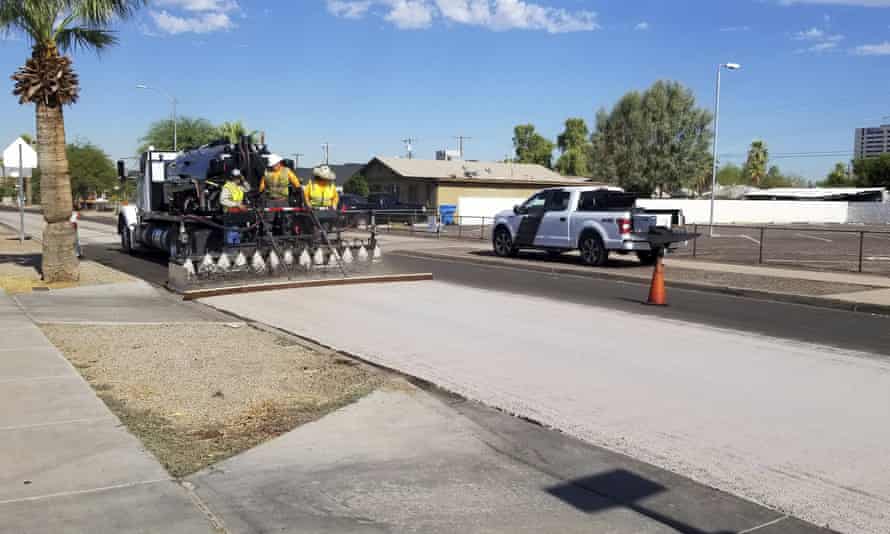Phoenix transportation department workers spray “cool pavement” over blacktop to reduce heat island effect.