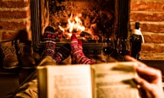 Couple reading a book with their feet up in front of fire