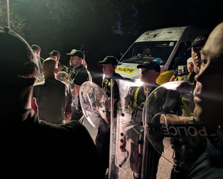 Police officers in riot gear at night at Eastney beach, Portsmouth.