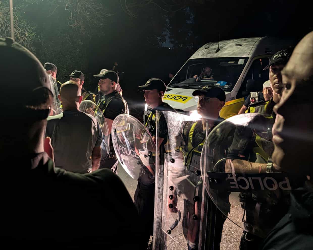 Police officers in riot gear at night at Eastney beach, Portsmouth.