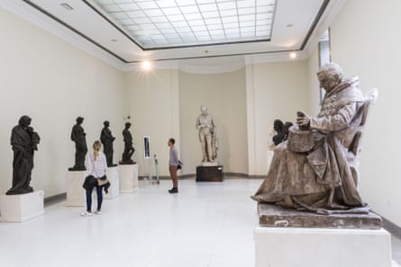 Sculptures in a well lit museum with people looking at them