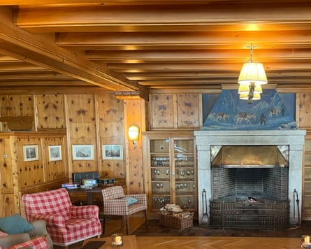 A woodpanelled lounge decorated in Alpine style with a fireplace and armchairs.