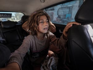 A child in a stained and worn jumper weeps in a car