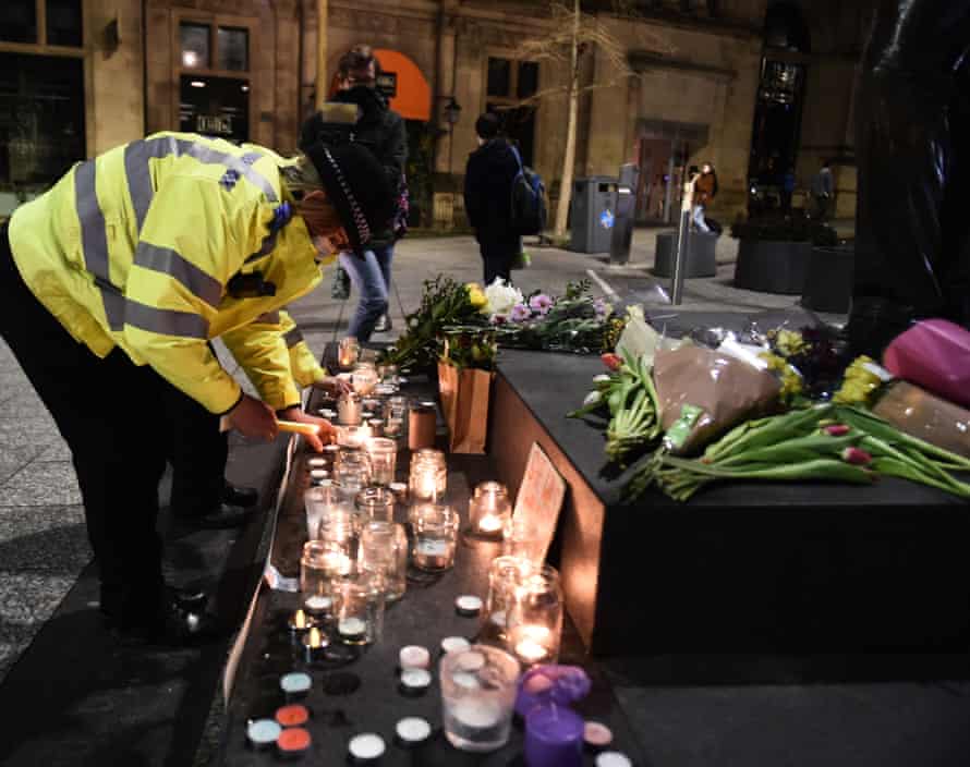 A female police officer lights a candle next to a makeshift memorial during a vigil for Sarah Everard on Market Square.