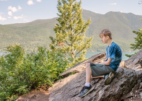 Graham, a boy on the autism spectrum, photographed on rocks above a lake by his mother in 2015