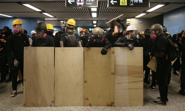 Anti-extradition bill protesters stand behind makeshift shields in Lam Tin station