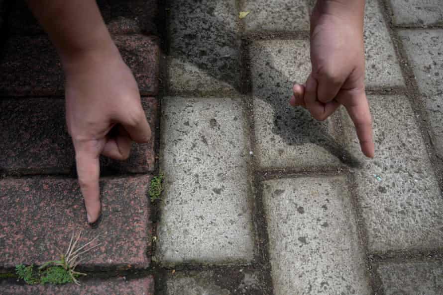 A worker points to a conventional red-coloured brick (left) and a brick containing recycled plastic waste (right), at the Rebricks brick-making factory in Jakarta.