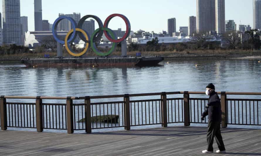 A man walks past the Tokyo 2020 Olympic rings wearing a mask