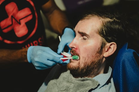 A close up view of a nurse brushing a man’s teeth