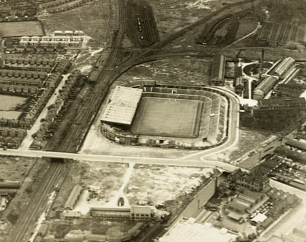 An aerial view of Old Trafford, showing the surrounding houses, railway tracks and factory units during the 1930s.