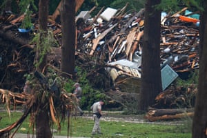 Officials inspect the banks of the Guadalupe River after flooding, with debris piled up in the distance