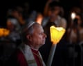 Pope Leo XIV holds a candle as he takes part in a torchlight procession in Lourdes on Sunday