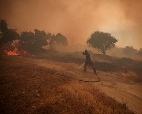 A fireman runs to extinguish a fire in an olive grove in the settlement of Zachouli, Greece.