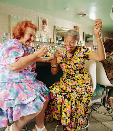 Woman in pink floral and woman in yellow floral sit with martini glasses